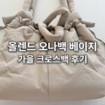 옆 조임끈을 당겨 도톰하게 모양을 잡은 올렌드 오나 소프트백 베이지